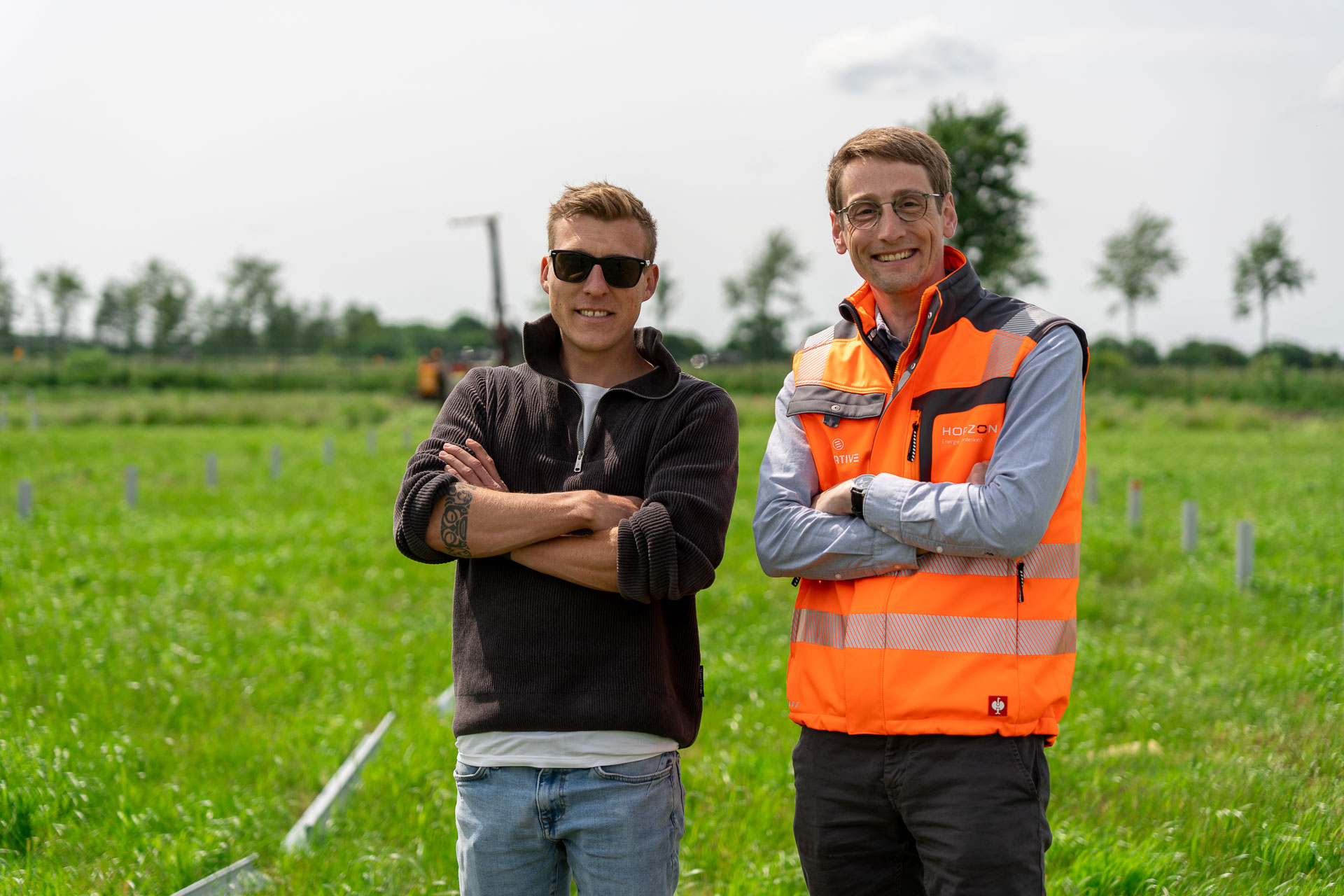 Die HORIZON-Geschäftsführer Melf Jensen und Thomas Kals stehen nebeneinander lächelnd mit verschränkten Armen vor einer grünen Wiese.