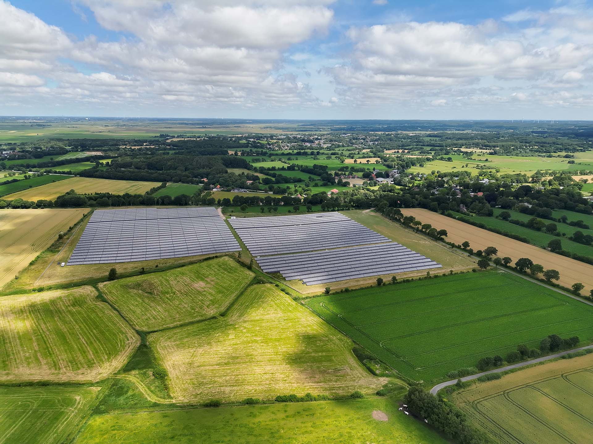 Eine Drohnenaufnahme der Photovoltaik-Freiflächenanlage in Nindorf-Farnewinkel inmitten grüner Felder.