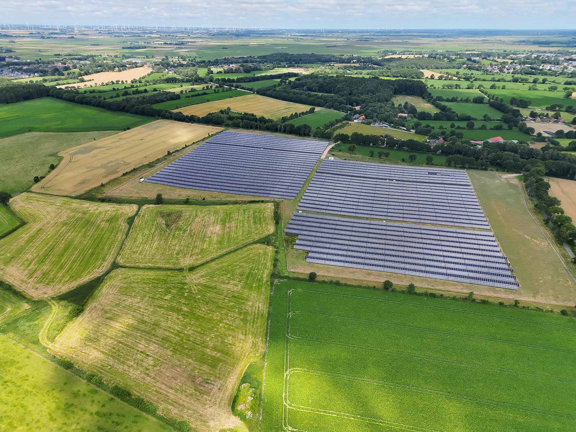 Eine Drohnenaufnahme der Photovoltaik-Freiflächenanlage in Nindorf-Farnewinkel inmitten grüner Felder.