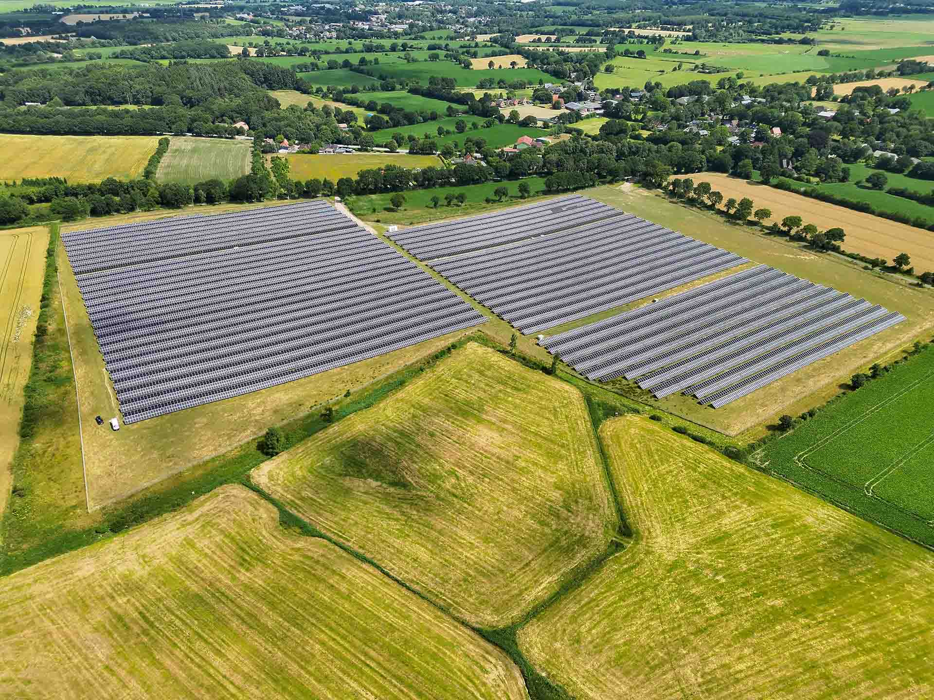 Eine Drohnenaufnahme der Photovoltaik-Freiflächenanlage in Nindorf-Farnewinkel inmitten grüner Felder.