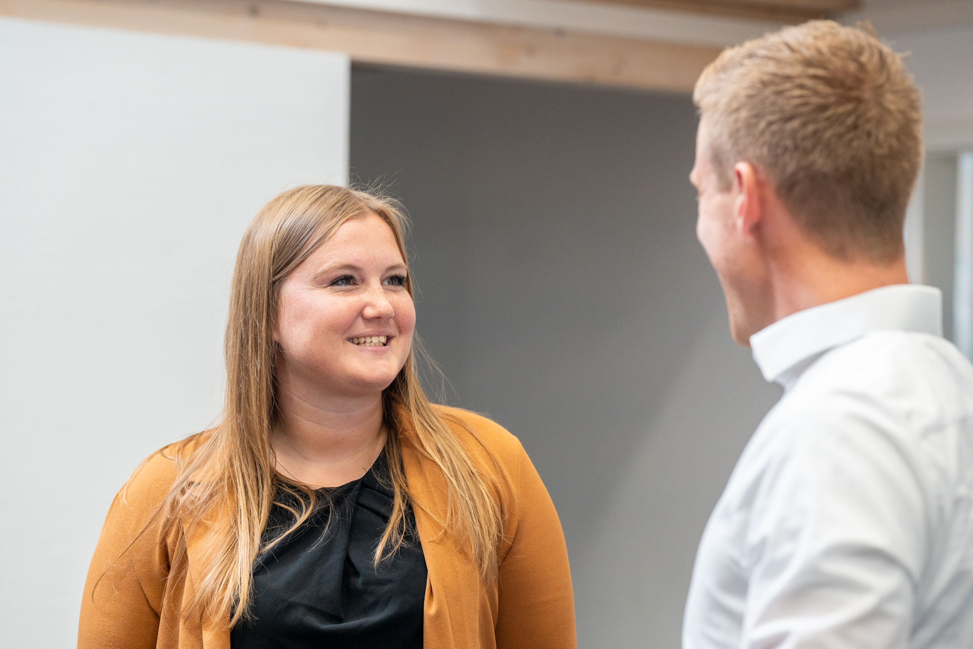 Eine HORIZON-Mitarbeiterin steht einem Mitarbeiter gegenüber. Beide unterhalten sich freundlich miteinander.